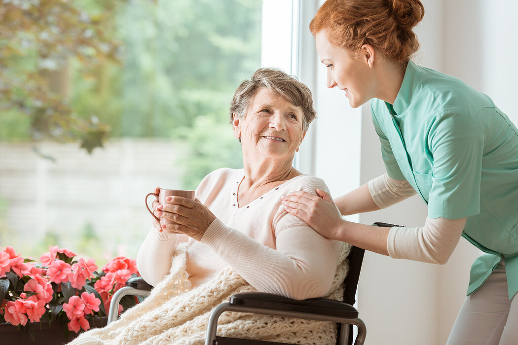 Seniorin im Rollstuhl mit Pflegekraft