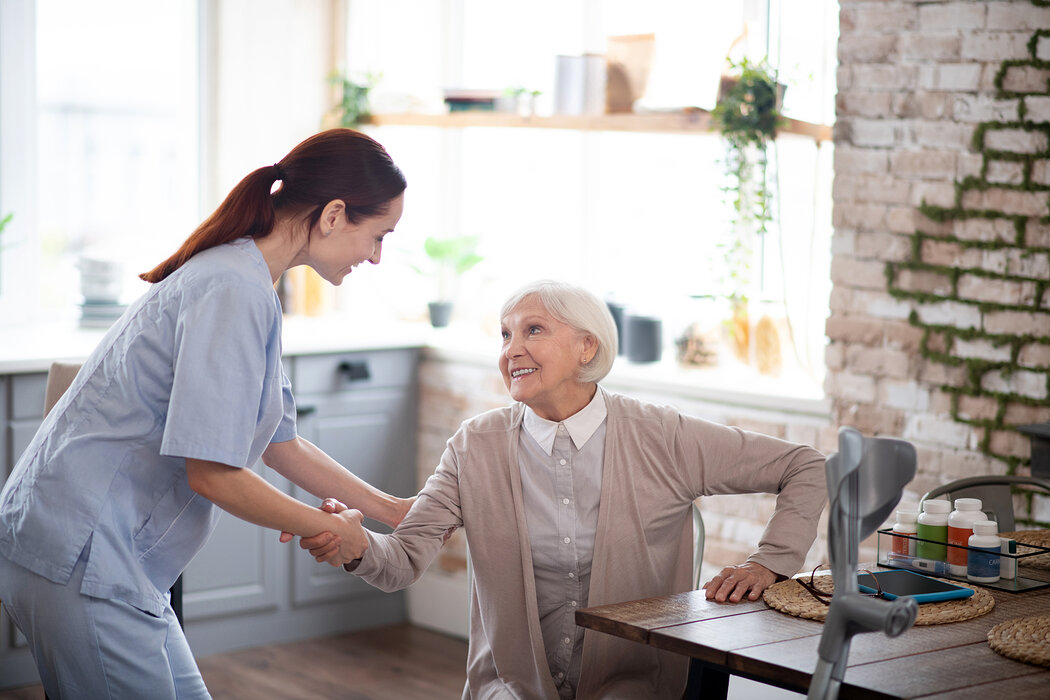 Betreuerin hilft Seniorin beim Aufstehen