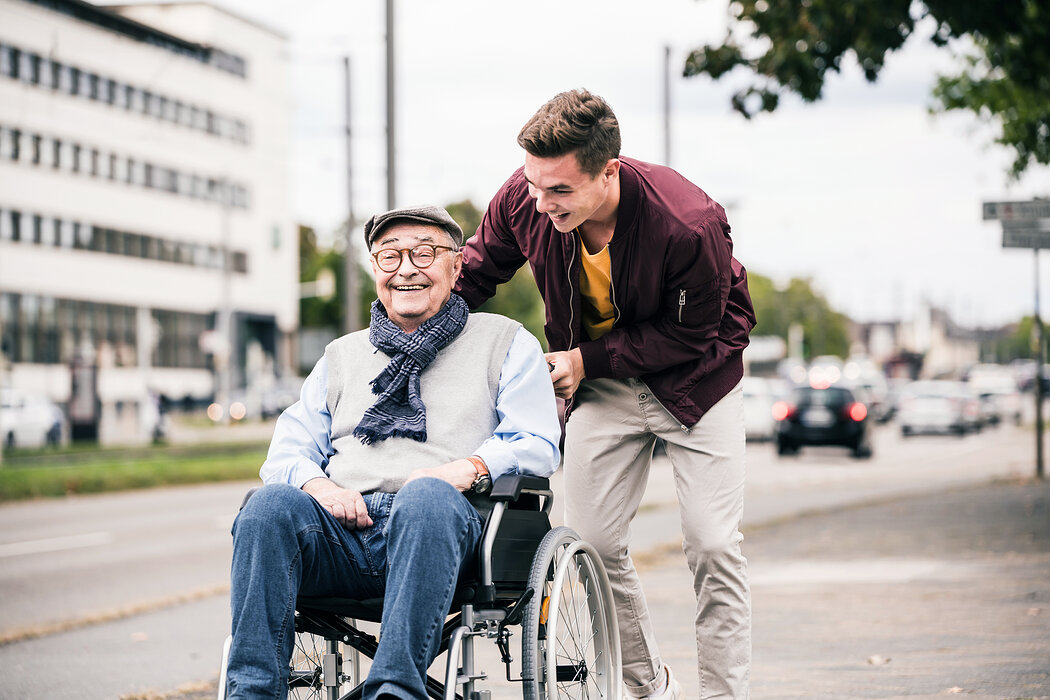 Senior im Rollstuhl mit jungem Mann