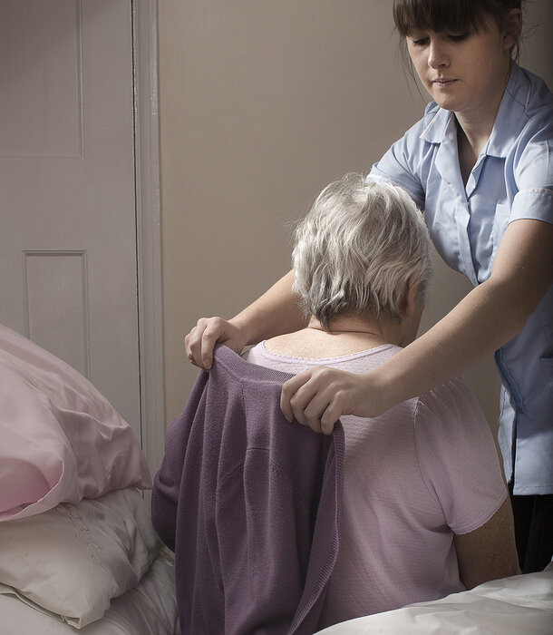 Seniorin bekommt Hilfe beim Anziehen